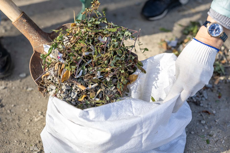 A close-up view of a large pile of shredded wood mulch, displaying a mixture of small, irregular pieces of light brown and tan wood. The mulch appears freshly prepared with a rough, textured surface, 